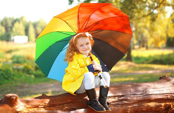 دختر کوچک پرتره پاییزی با چتر رنگارنگ در فضای باز در پارک