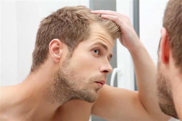 مرد خوش تیپی اصلاح نشده در حمام به آینه نگاه می کند