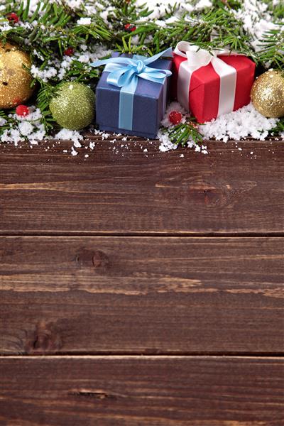 هدایای کریسمس روی تخته چوبی با درخت کریسمس و برف