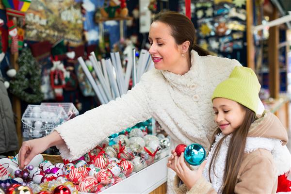 دختر کوچک با مادر خندان در بازار کریسمس روی زن تمرکز کنید