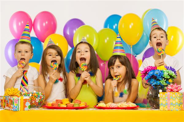 گروهی از بچه های کوچک شاد و سرگرم کننده در مهمانی تولد مفهوم تعطیلات