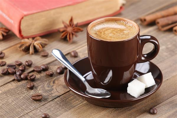 فنجان قهوه قهوه ای در نعلبکی در پس زمینه تخته های چوبی