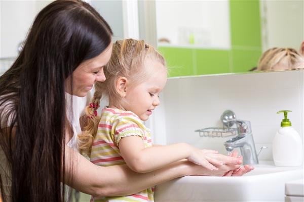 کودک و مادر در حال شستن دست ها با صابون در حمام