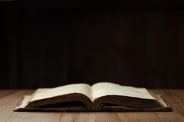 تصویری از یک کتاب مقدس مقدس در زمینه چوبی در یک فضای تاریک