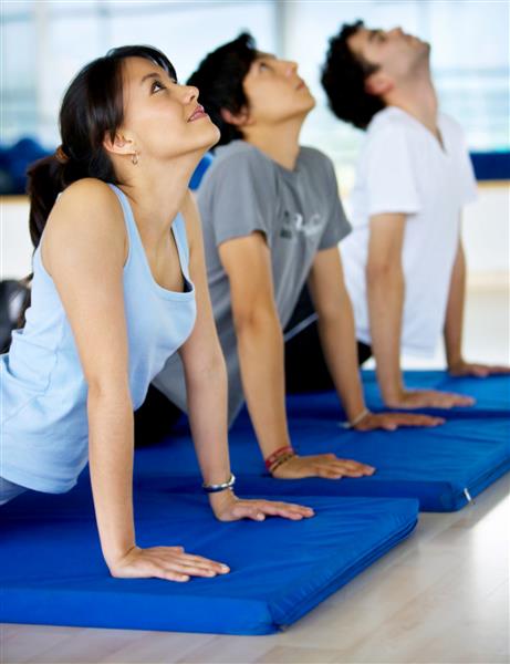 گروهی از افراد در ورزشگاه تمرینات یوگا انجام می دهند