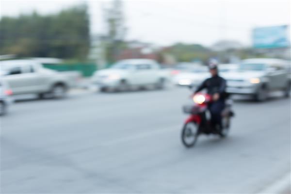 رانندگی اتومبیل و موتور سیکلت در جاده با ترافیک در شهر پس زمینه تاریک انتزاعی