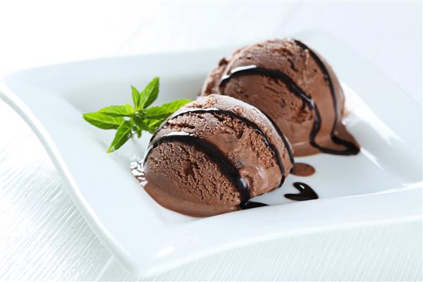بستنی شکلاتی شیرین در بشقاب در زمینه چوبی سفید