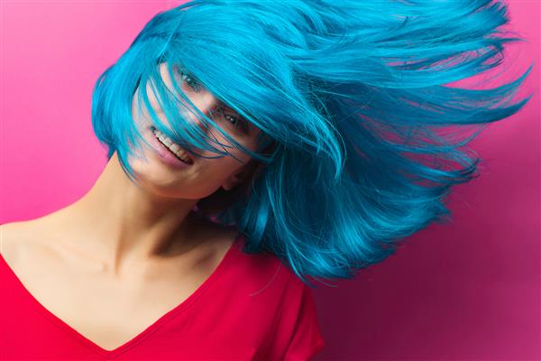 پرتره استودیویی از یک دختر زیبا با موهای فیروزه ای در حرکت در زمینه صورتی