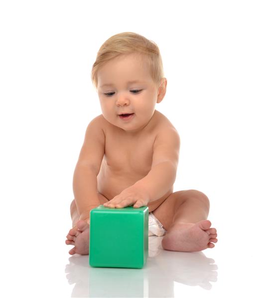کودک نوپای کودک با اسباب بازی آجری سبز روی زمین سفید