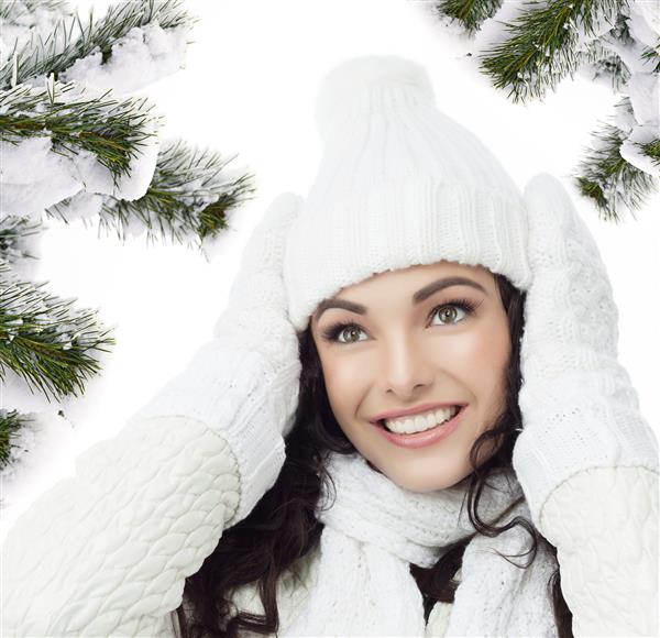 مدل زن با لباس گرم و خندان در کنار درخت کریسمس