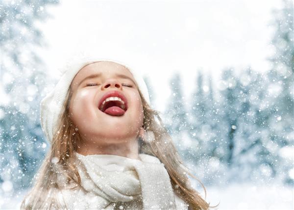 دختر بچه خوشحال که در پیاده روی زمستانی برفی قرار دارد