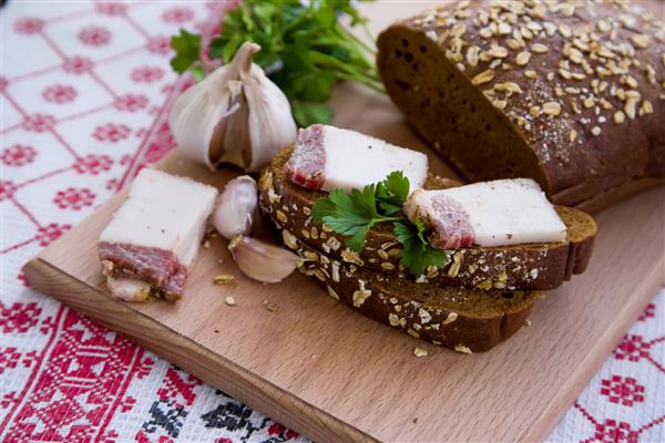 غذاهای ملی اوکراین نان قهوه ای تکه های گوشت روی سفره گلدوزی شده روی میز چوبی