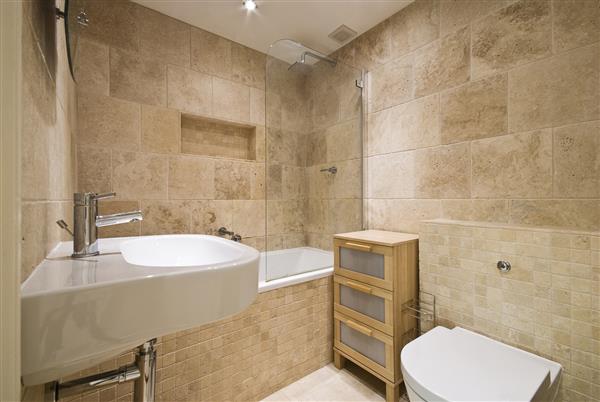 حمام لوکس مدرن با کاشی های سنگی از سنگ مرمر بژ و مجموعه سرامیک سفید