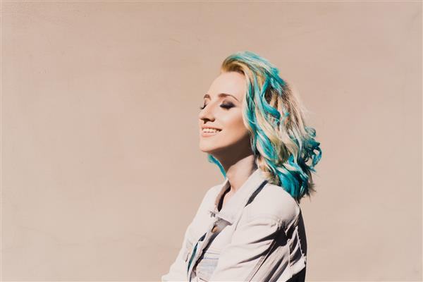 تصویری از نمای نزدیک از یک دختر هیپستر زیبا و جوان بلوند با موهای آبی رنگی