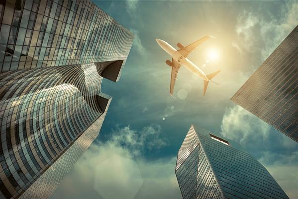 هواپیمایی که بر فراز ساختمانهای اداری شیشه و فولاد مدرن پرواز می کند