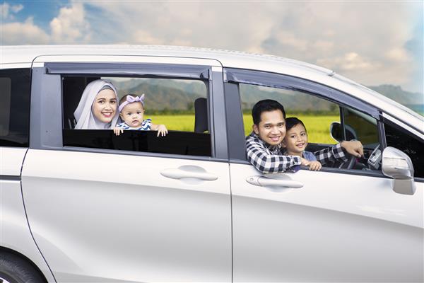 پرتره خانواده مسلمان هنگام رانندگی برای مسافرت در تعطیلات از پنجره ماشین به بیرون نگاه می کنند
