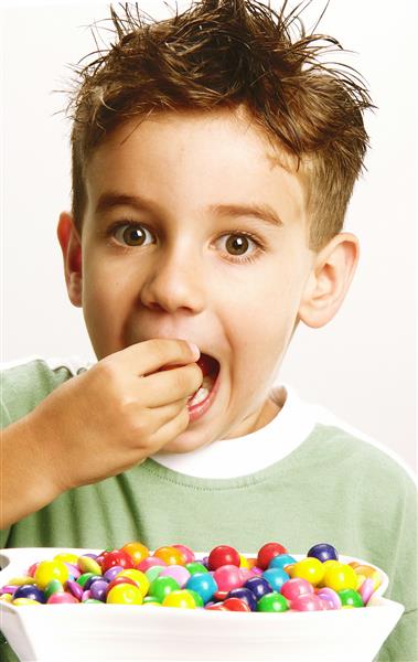 پسر کوچک در حال خوردن آب نبات در پس زمینه سفید