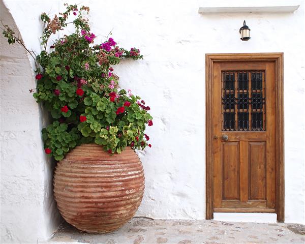 درب خانه چوبی و گلدان گل بزرگ در یونان