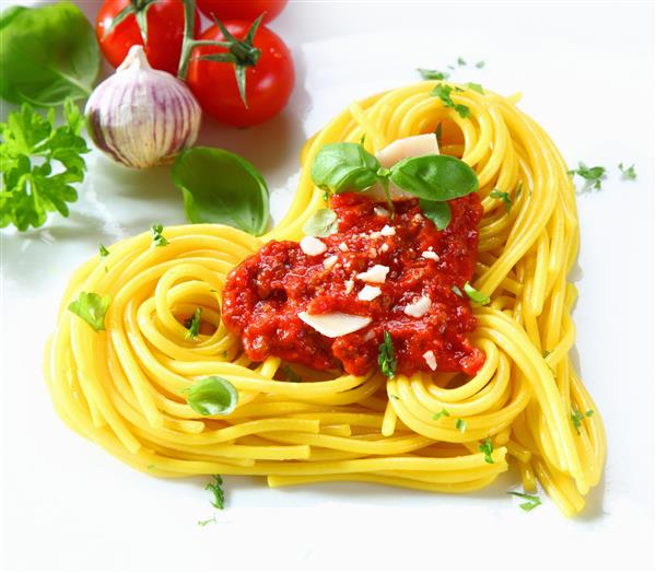 اسپاگتی پخته شده به شکل قلب چیده شده با سس گوجه فرنگی و ریحان تازه