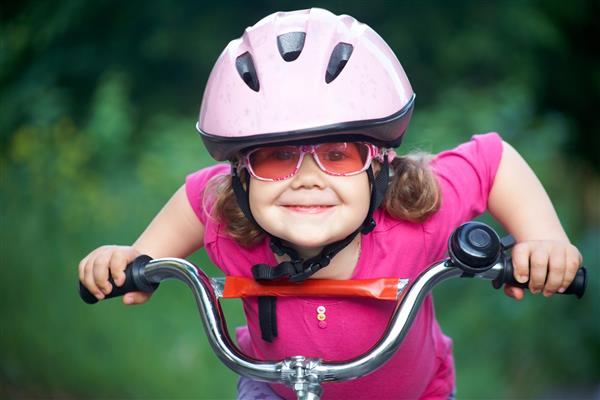 پرتره یک دختر کوچک با دوچرخه در پارک تابستانی در فضای باز