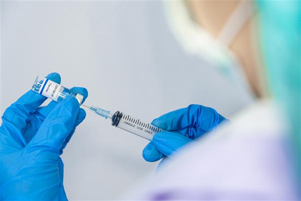 پزشک در حال آماده سازی برای آزمایش تزریق بالینی واکسیناسیون کروناویروس بر روی انسان است