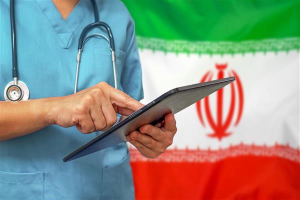 جراح یا پزشک از تبلت دیجیتالی در پس زمینه پرچم ایران استفاده می کند
