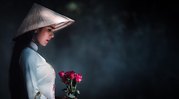 دختر ویتنامی با لباس سفید با کلاه و گل رز قرمز در دستان هم