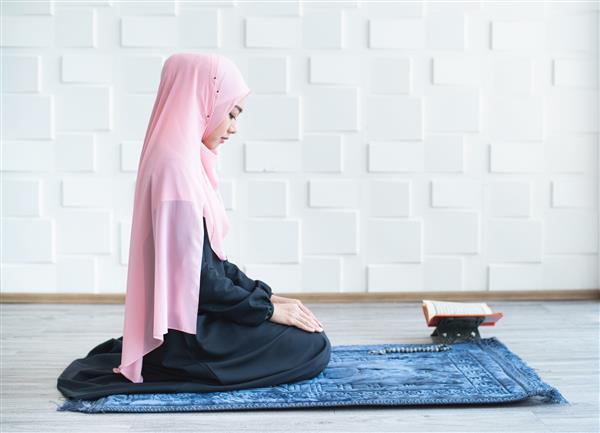 زن مسلمان با حجاب نماز می خواند و روی حصیر در داخل خانه نماز می خواند