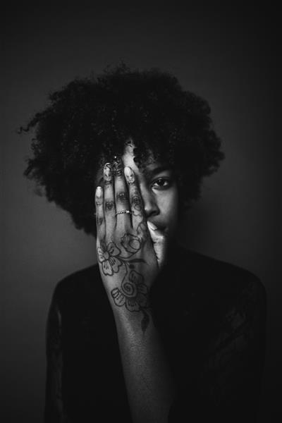 زنی با موهای آفریقایی سیاه و خالکوبی روی دست