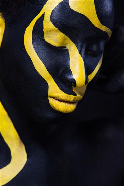 زنی با رنگ بدن مشکی هنری مدلی شگفت انگیز با آرایش زرد چهره نزدیک