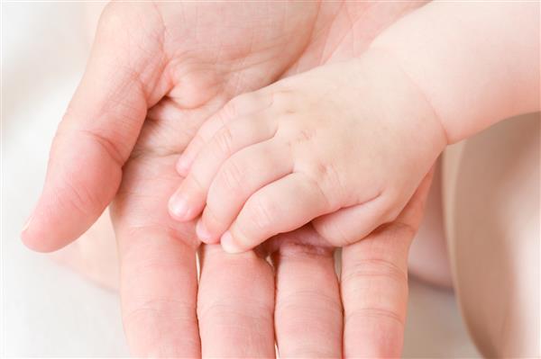 دست نوزاد قفقازی در کف دست پدر