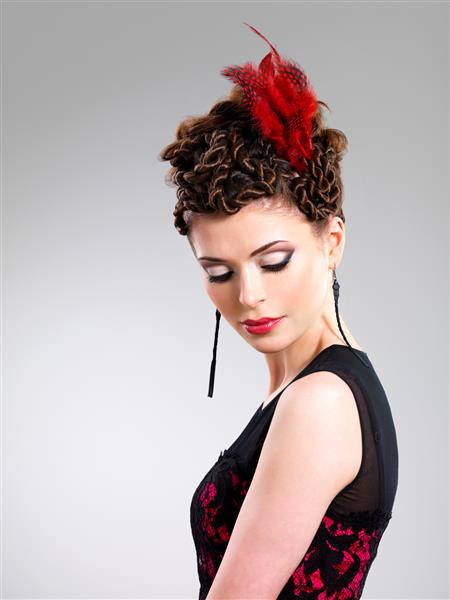 زن بالغ زیبا با مدل موی مد با پر قرمز در موها