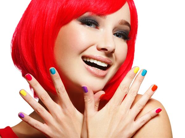 چهره متعجب یک زن جوان زیبا با موهای قرمز روشن و ناخن های رنگارنگ