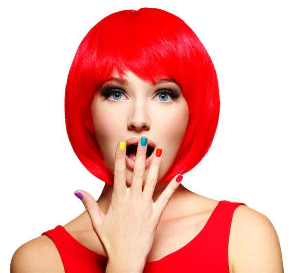 چهره متعجب یک زن جوان زیبا با موهای قرمز روشن و ناخن های رنگارنگ