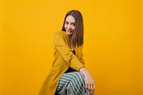 مدل زن دوست داشتنی در ژاکت روشن با لبخند صمیمانه زن قفقازی پر زرق و برق با لباس های زرد