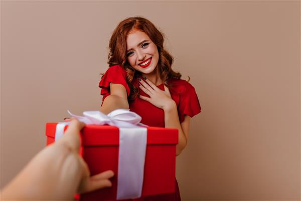 دختر زیبای خجالتی با لباس قرمز که در جشن تولدش ژست گرفته است عکس داخلی زن الهام گرفته از فرفری با هدیه سال نو