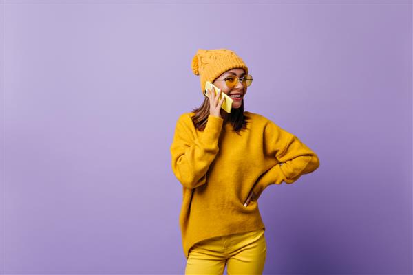 دختر عاشق رنگ نارنجی و ژست گرفتن برای عکس های جدید با لباس شیک است مدل صحبت کردن با تلفن زرد دوستانه لبخند می زند