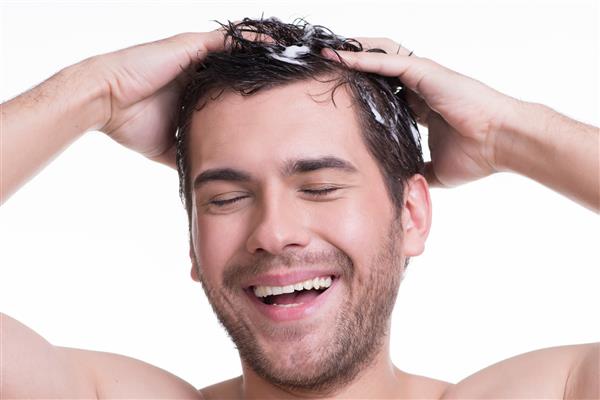 مرد جوان شاد و خندان در حال شستن مو با چشمان بسته - جدا شده روی سفید