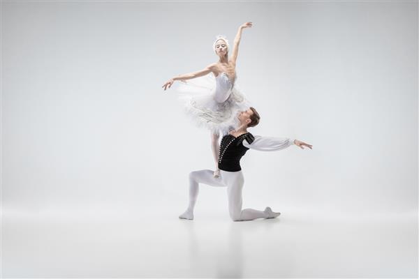 زوج رقصنده باله کلاسیک برازنده در حال رقصیدن با لباس های سفید لطیف مانند شخصیت های قو سفید مفهوم لطف هنرمند حرکت عمل و حرکت