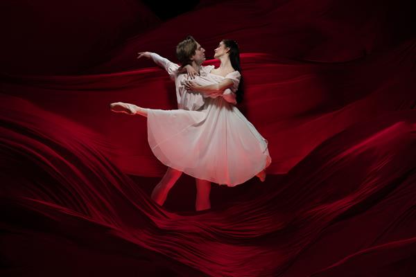 رمان رقصندگان جوان و برازنده باله روی دیوار پارچه ای قرمز در اکشن کلاسیک هنر حرکت عمل انعطاف پذیری مفهوم الهام زوج قفقازی انعطاف پذیر با امواج قرمز مواج
