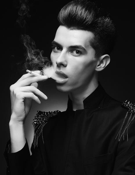 مرد جوان شیک در حال کشیدن سیگار شات استودیویی