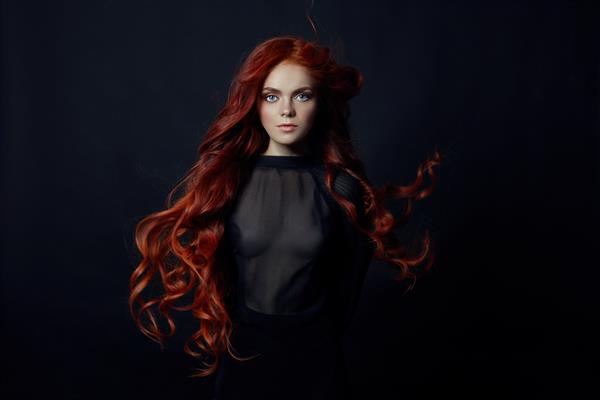 پرتره زن زیبا مو قرمز با موهای بلند در پس زمینه مشکی دختری عالی با چشمان آبی پوست تمیز و زیبا آرایش طبیعی زیبا موهای قرمز