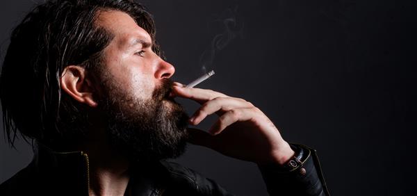 مرد ریشو سیگار می کشد مرد شیک پوش با کت چرمی با سیگار هیپستر سیگاری