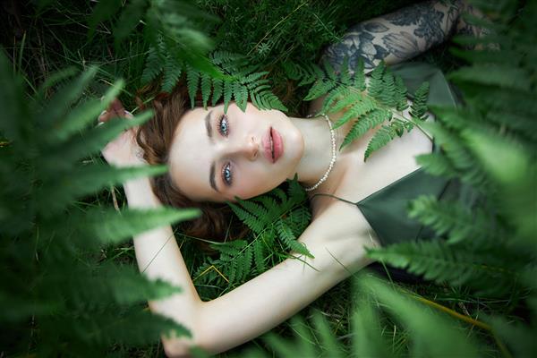 پرتره عاشقانه زنی در سرخس در جنگل آرایش طبیعی زن هنری در حال استراحت در طبیعت بیشه های سرخس سبز