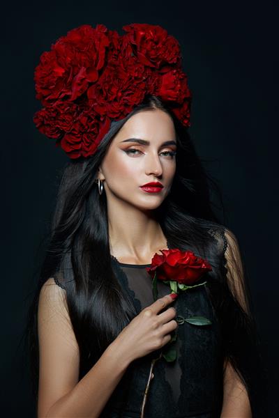 پرتره زیبایی زن سبزه با تاجی از گل های رز روی سرش آرایش قرمز روشن و رژ لب گل های رز در دستان یک زن