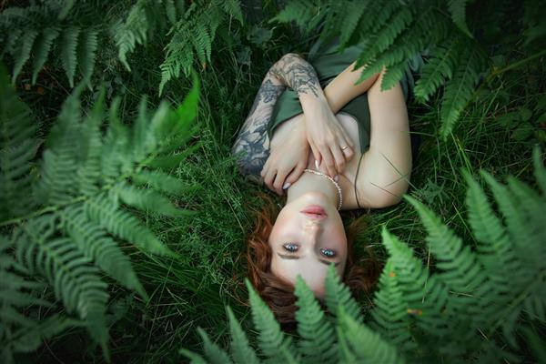 پرتره عاشقانه زنی در سرخس در جنگل آرایش طبیعی زن هنری در حال استراحت در طبیعت بیشه های سرخس سبز