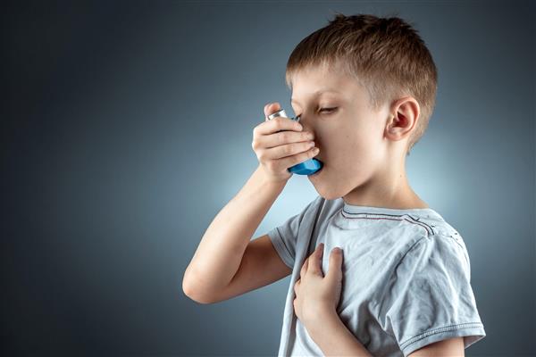 پرتره پسری که از دستگاه تنفسی آسم برای درمان بیماری های التهابی تنگی نفس استفاده می کند مفهوم درمان سرفه آلرژی بیماری های دستگاه تنفسی