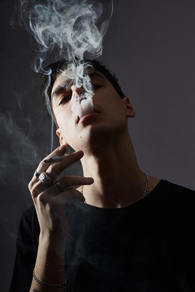 پرتره یک مرد جوان مد سیگاری در متضاد سیاه و سفید