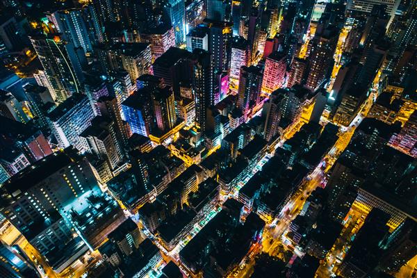 عکس هوایی از مناظر شهری با ساختمان های مرتفع که نور را در طول شب پخش می کنند