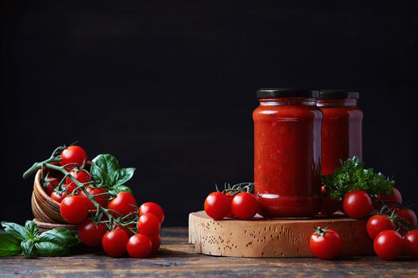 سس گوجه فرنگی خانگی در یک ظرف شیشه ای گوجه فرنگی و سبزیجات کنار آن
